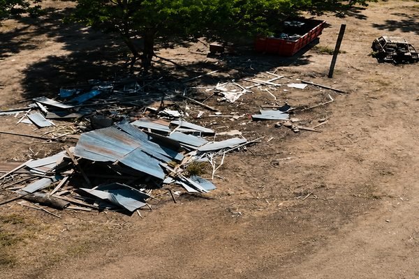 Before: Construction debris and scrap metal scattered across a dirt lot before dumpster rental cleanup.